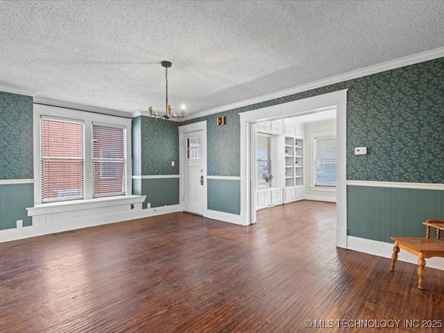 interior space featuring built in features, a chandelier, dark hardwood / wood-style flooring, ornamental molding, and a textured ceiling