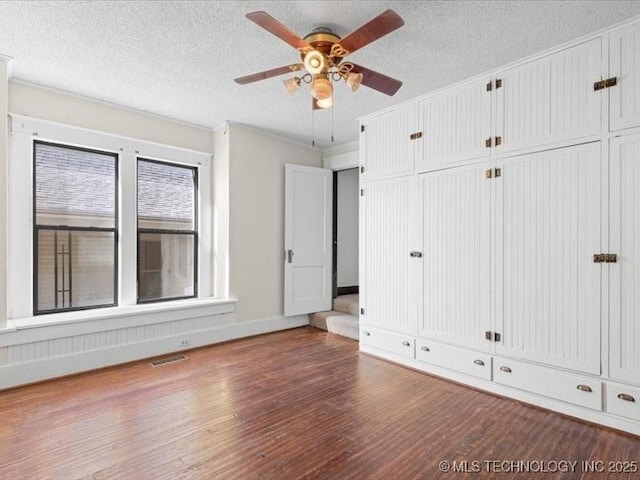 unfurnished bedroom with ceiling fan, dark hardwood / wood-style flooring, and a textured ceiling