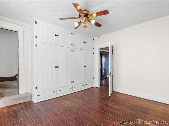 unfurnished bedroom with a textured ceiling, dark hardwood / wood-style floors, and ceiling fan