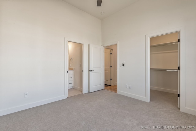 unfurnished bedroom featuring a walk in closet, light colored carpet, high vaulted ceiling, and a closet