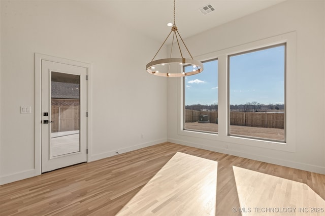 unfurnished dining area featuring light hardwood / wood-style flooring and a notable chandelier