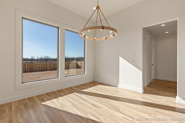 unfurnished dining area featuring wood-type flooring and an inviting chandelier