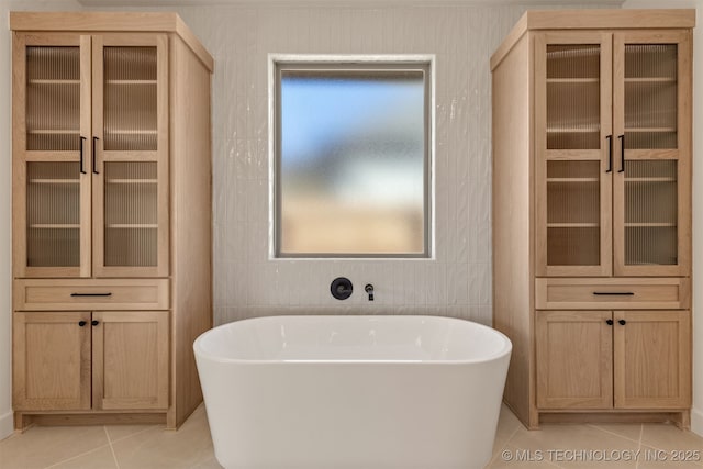 bathroom featuring tile walls, tile patterned flooring, and a bathing tub