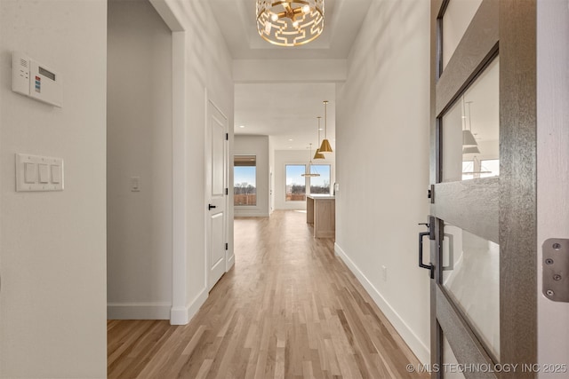 hallway with light hardwood / wood-style floors and a notable chandelier