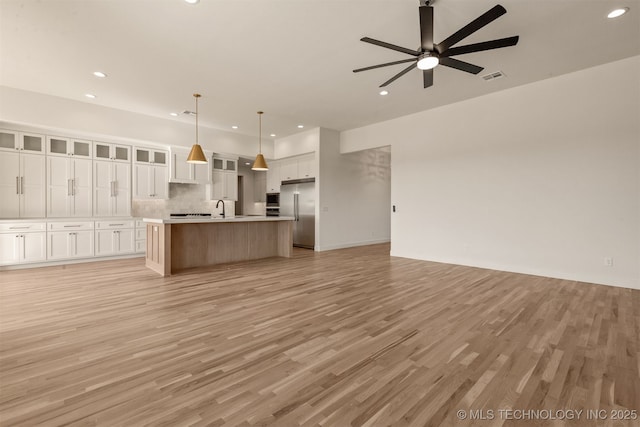 unfurnished living room featuring sink, light hardwood / wood-style flooring, and ceiling fan