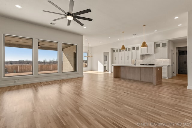 unfurnished living room with ceiling fan, sink, and light hardwood / wood-style flooring