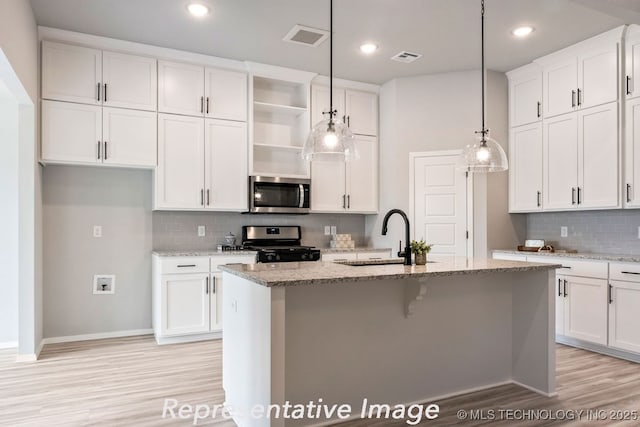 kitchen with sink, pendant lighting, stainless steel appliances, a kitchen island with sink, and white cabinets