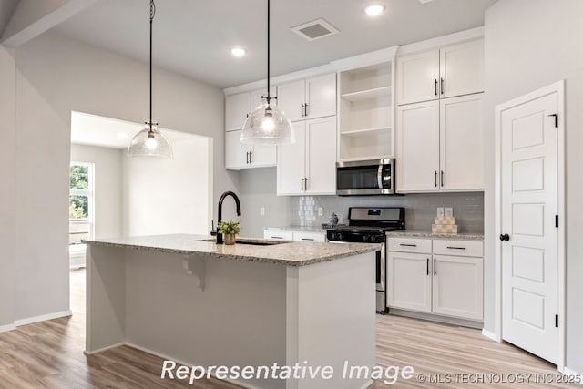 kitchen featuring sink, white cabinetry, decorative light fixtures, stainless steel appliances, and a kitchen island with sink