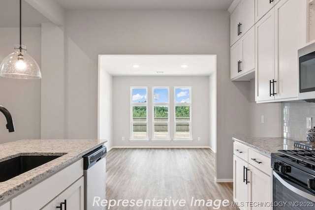 kitchen featuring white cabinetry, light stone countertops, appliances with stainless steel finishes, and backsplash