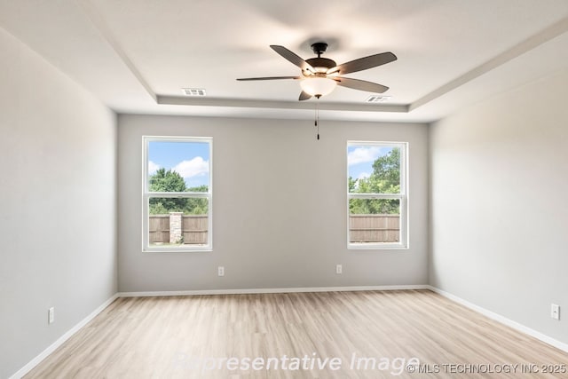 spare room featuring ceiling fan, light hardwood / wood-style floors, and a tray ceiling