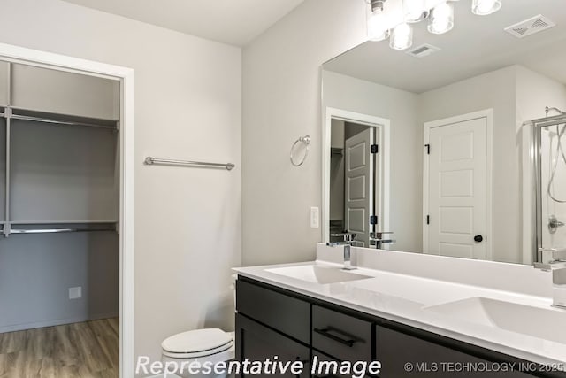 bathroom with hardwood / wood-style flooring, vanity, toilet, and a shower with shower door