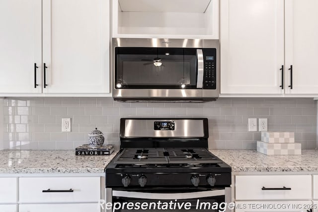 kitchen with tasteful backsplash, white cabinetry, light stone counters, and range with gas cooktop