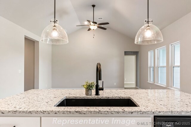 kitchen featuring pendant lighting, sink, light stone counters, and lofted ceiling