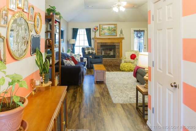 living room with lofted ceiling, dark hardwood / wood-style floors, ceiling fan, and a brick fireplace