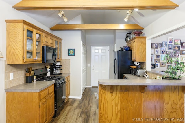 kitchen featuring tasteful backsplash, lofted ceiling with beams, black appliances, kitchen peninsula, and dark wood-type flooring