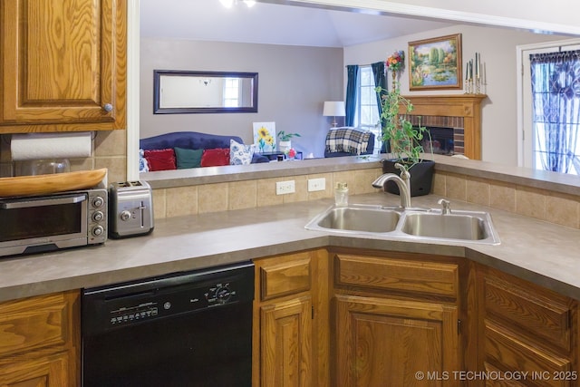 kitchen with black dishwasher, sink, a fireplace, and decorative backsplash