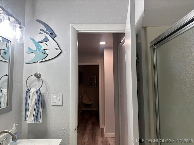 bathroom with hardwood / wood-style flooring, vanity, and an enclosed shower