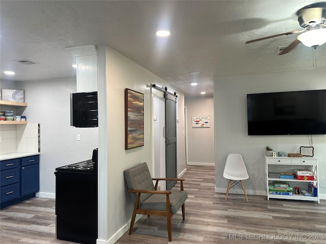 interior space with a barn door, hardwood / wood-style floors, a textured ceiling, and ceiling fan