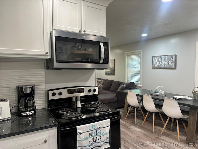 kitchen featuring light hardwood / wood-style flooring, black electric range, and white cabinets