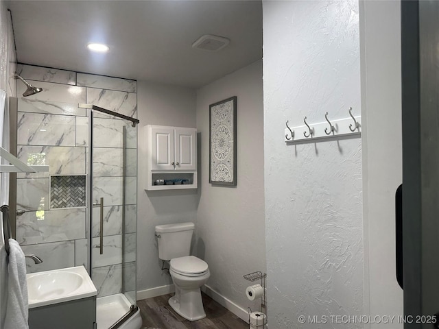 bathroom with a shower with door, vanity, hardwood / wood-style flooring, and toilet