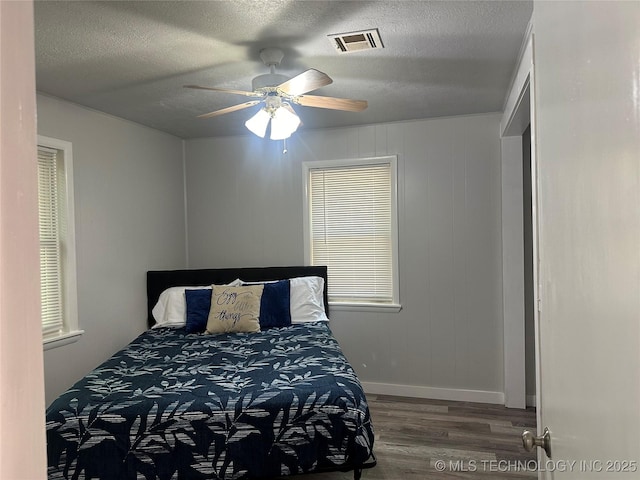 bedroom with a textured ceiling, dark hardwood / wood-style floors, and ceiling fan