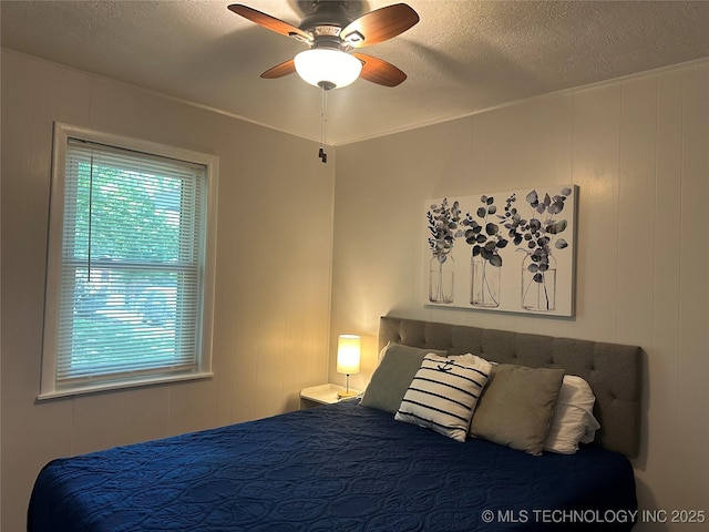 bedroom featuring wooden walls, a textured ceiling, and ceiling fan