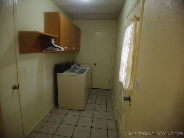 laundry room with cabinets, a textured ceiling, and light tile patterned floors