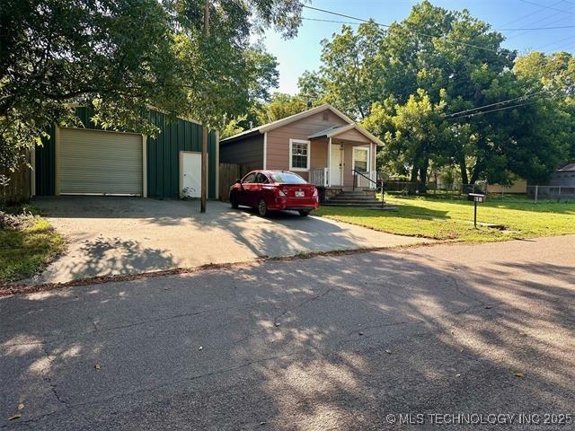 view of front of property featuring a garage, an outdoor structure, and a front yard