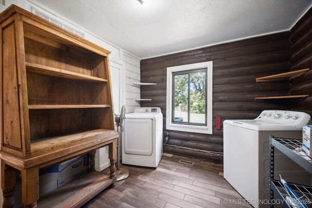 washroom featuring dark hardwood / wood-style flooring, rustic walls, a textured ceiling, and independent washer and dryer