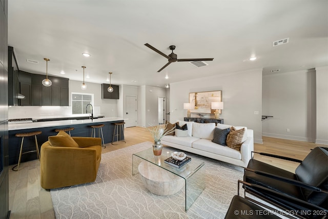 living room featuring sink, ceiling fan, and light wood-type flooring