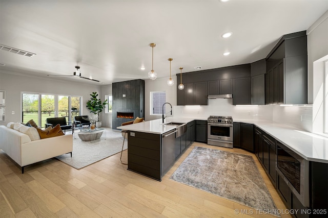 kitchen with pendant lighting, a tile fireplace, stainless steel appliances, kitchen peninsula, and light wood-type flooring