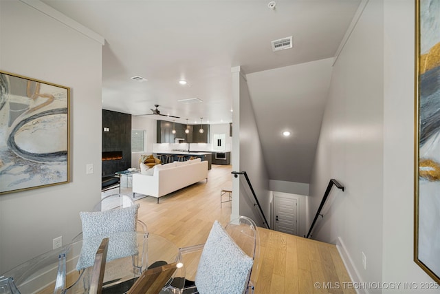 living room with ceiling fan, a tile fireplace, and light wood-type flooring