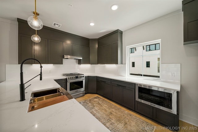 kitchen with pendant lighting, high end stainless steel range oven, light stone counters, tasteful backsplash, and light hardwood / wood-style floors