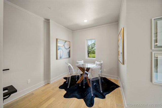 dining area with ornamental molding and light hardwood / wood-style floors