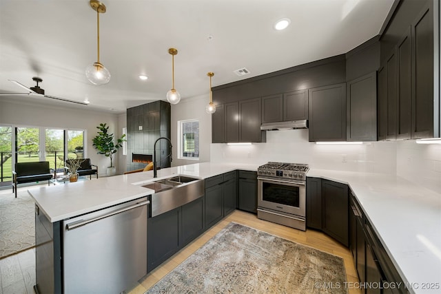 kitchen with sink, tasteful backsplash, decorative light fixtures, kitchen peninsula, and stainless steel appliances