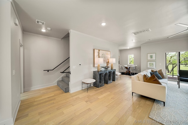 living room with crown molding and light hardwood / wood-style floors