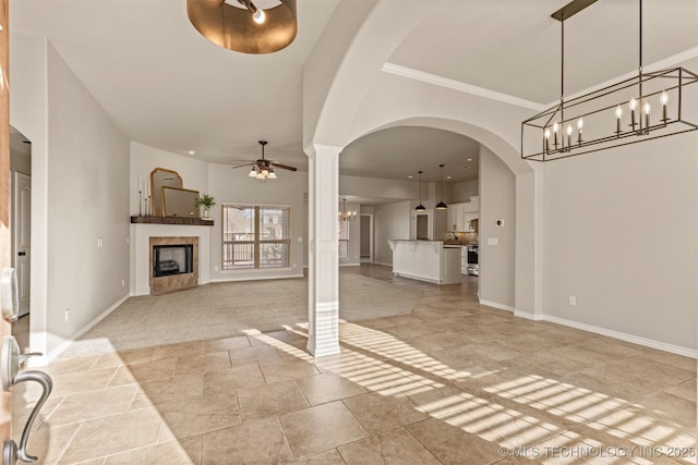 unfurnished living room with decorative columns, ornamental molding, and ceiling fan with notable chandelier