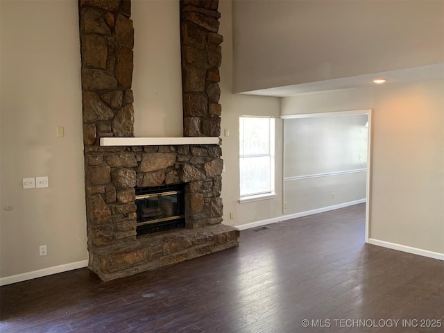 unfurnished living room with a stone fireplace and dark hardwood / wood-style floors