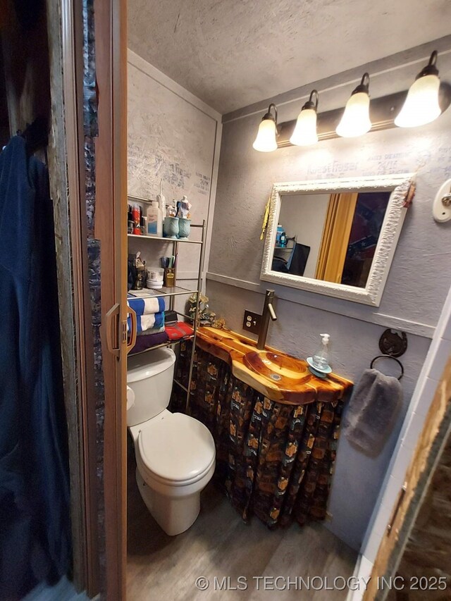 bathroom with wood finished floors, toilet, and a textured ceiling