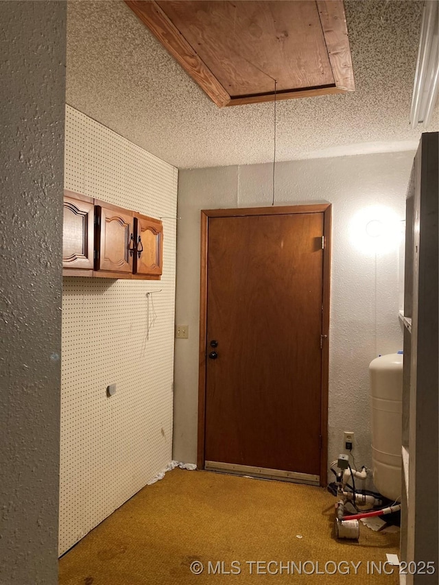 doorway with a textured ceiling and light colored carpet