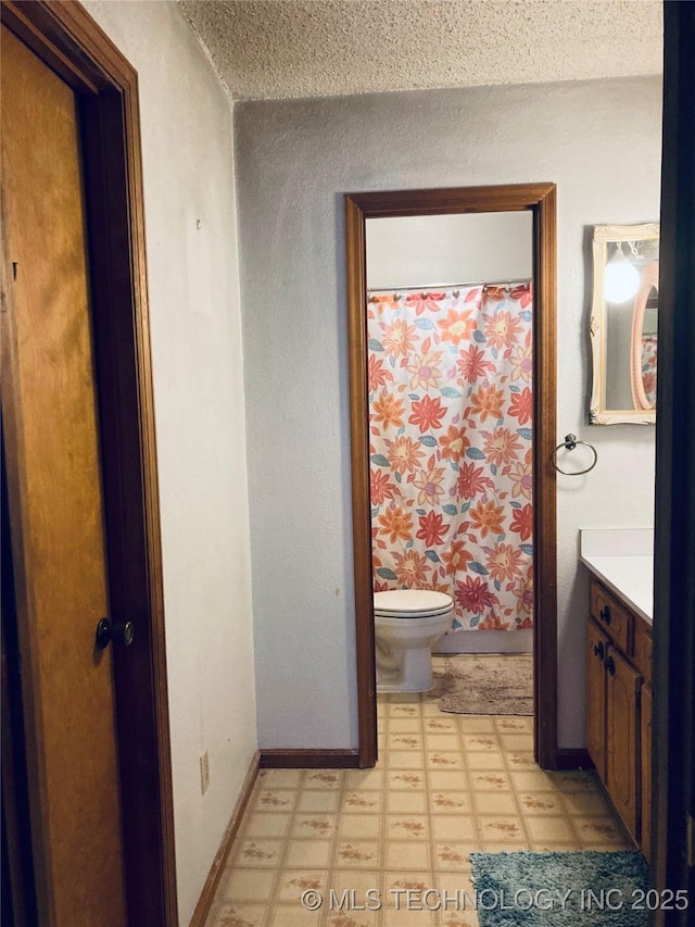 bathroom featuring baseboards, toilet, tile patterned floors, a textured ceiling, and vanity