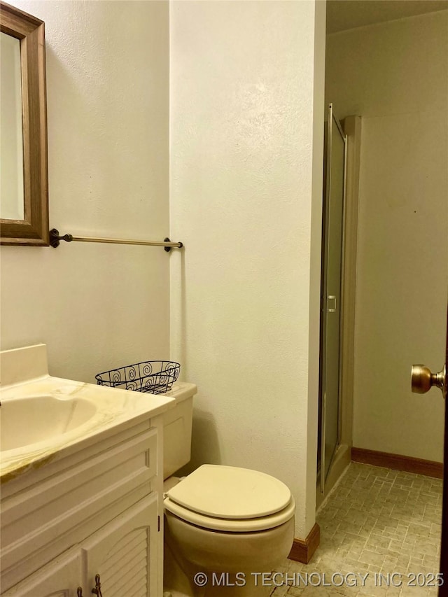 full bath featuring toilet, a shower stall, baseboards, and vanity