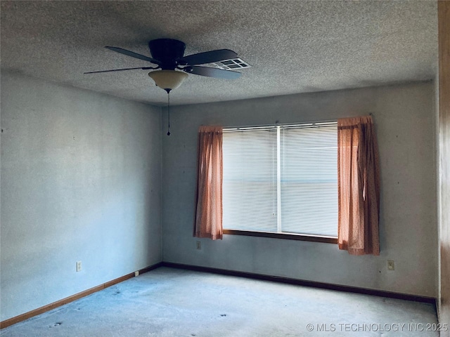 spare room featuring a textured ceiling, ceiling fan, light colored carpet, visible vents, and baseboards