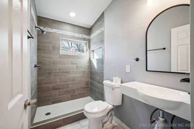 bathroom featuring tile patterned floors, toilet, and a tile shower