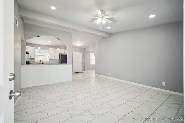 unfurnished living room featuring vaulted ceiling, sink, and ceiling fan