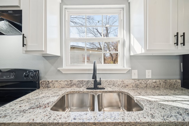 kitchen featuring light stone counters, extractor fan, white cabinetry, and sink