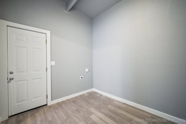 empty room featuring lofted ceiling with beams and light wood-type flooring