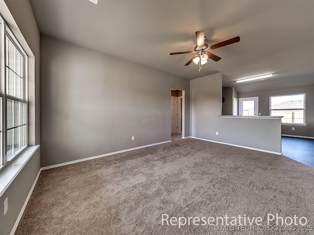 spare room featuring dark carpet and ceiling fan