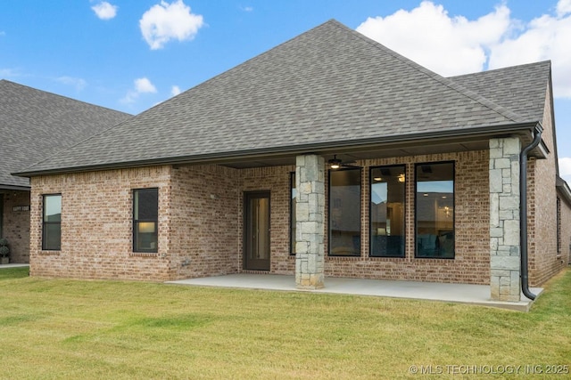 rear view of house with a yard, brick siding, roof with shingles, and a patio