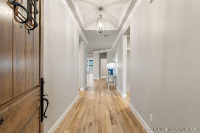 hall featuring light wood-style flooring, baseboards, crown molding, and a textured wall